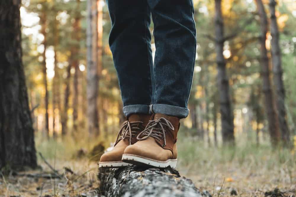 A man in the woods wearing a pair of hiking boots and jeans.