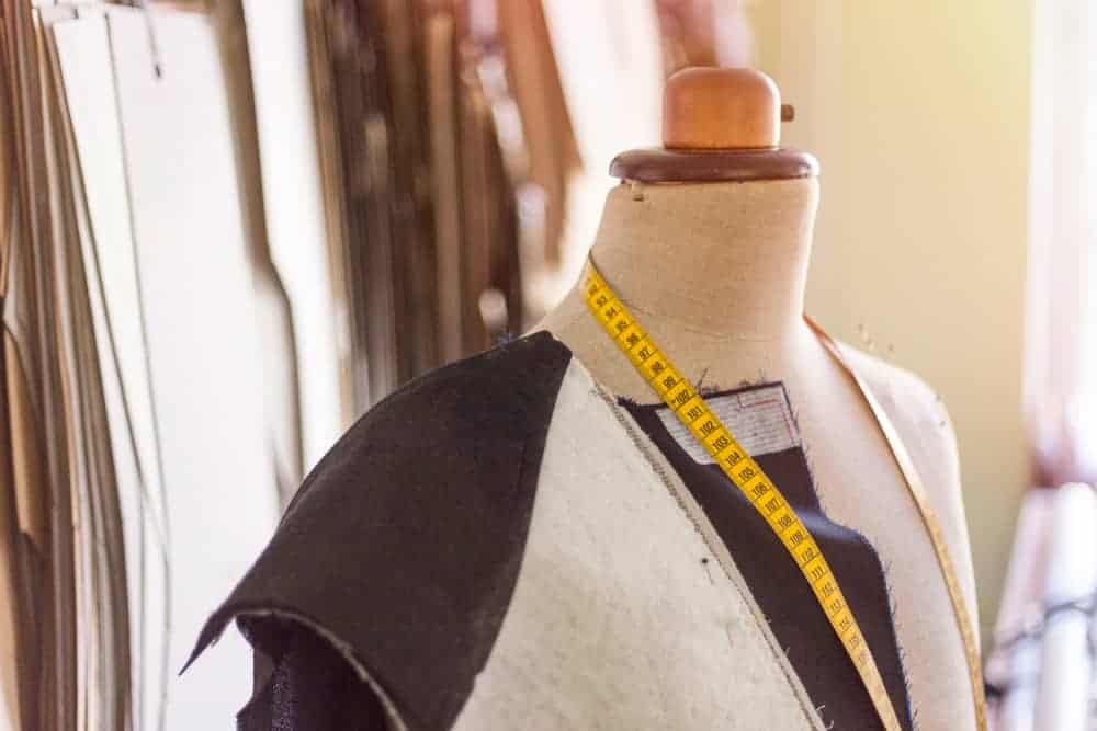 Mannequin wearing tailored suit jacket pieces and tape measure.