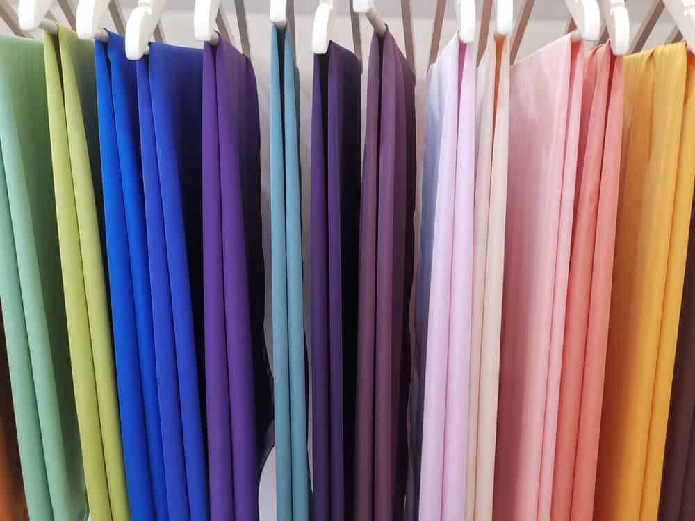 Multicolored satin fabric on hangers.