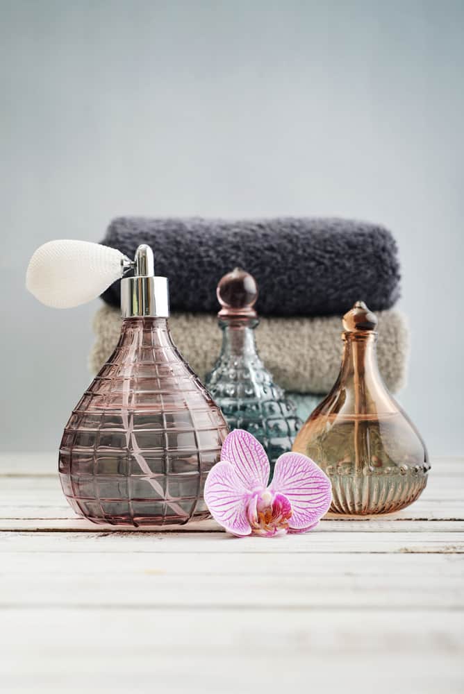 Perfume bottles and a pile of towels over a wooden surface.