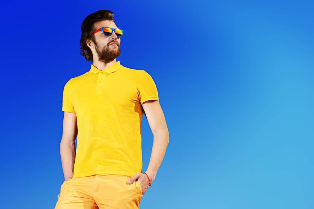 A man wearing a matching neon yellow shirt and shorts against a blue sky.