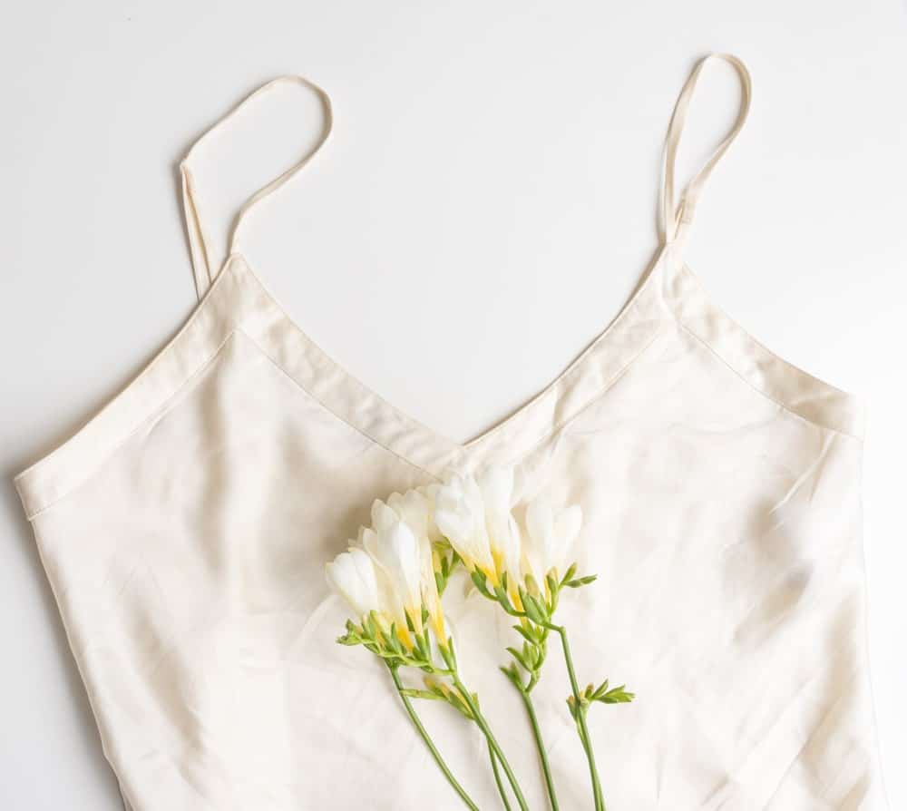A silky white camisole with a cluster of white flowers.