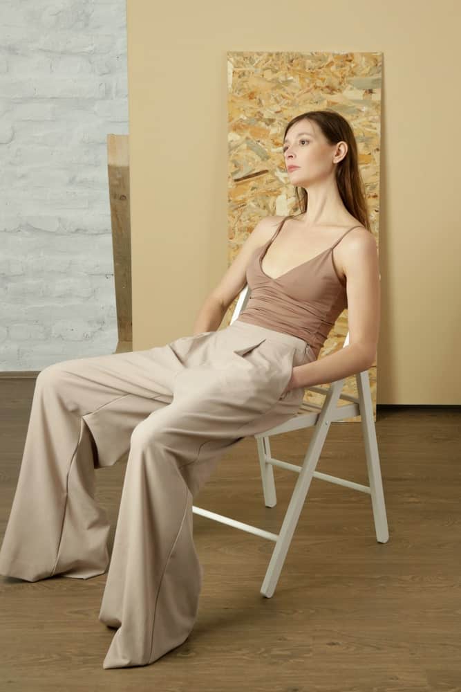 This is a close look at a woman wearing a pair of beige pants with her beige camisole.