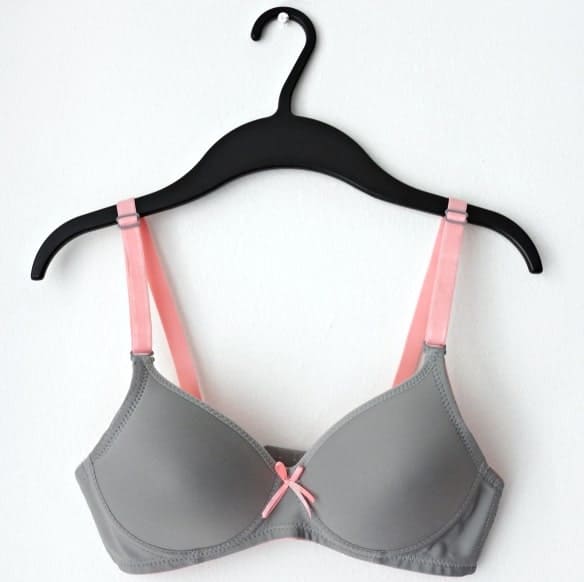 This is a close look at a gray and pink bra hanging on a hanger.