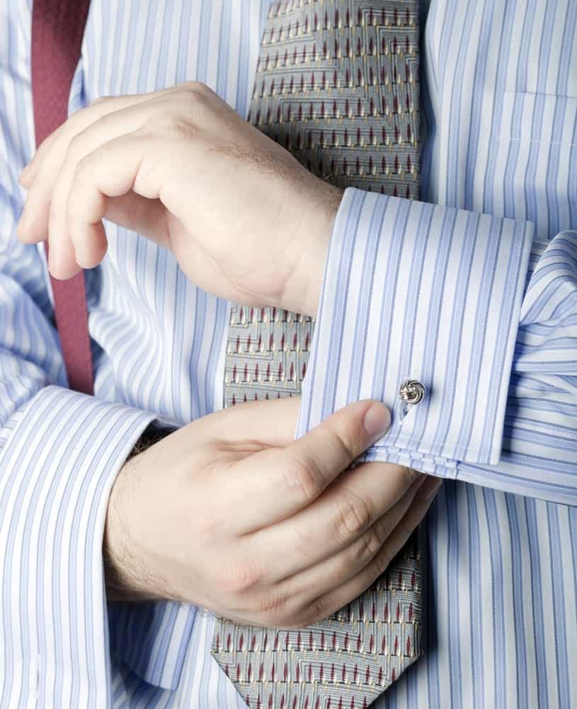 This is a close look at a man wearing a striped shirt with French cuffs.
