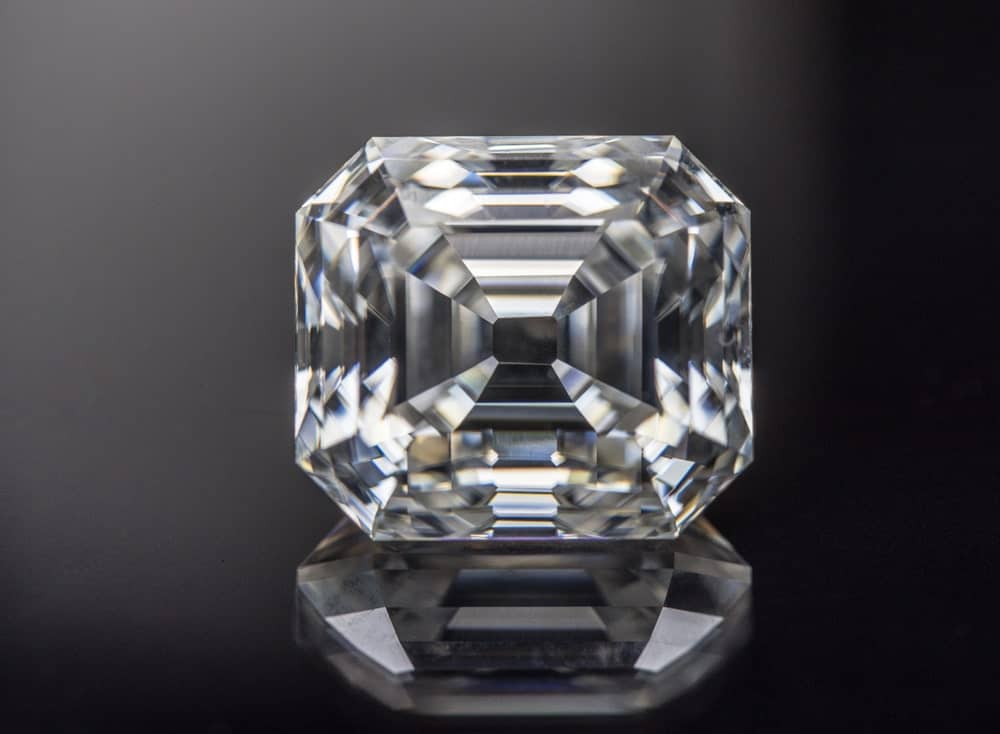 This is a close look at an Asscher cut diamond on a dark surface.