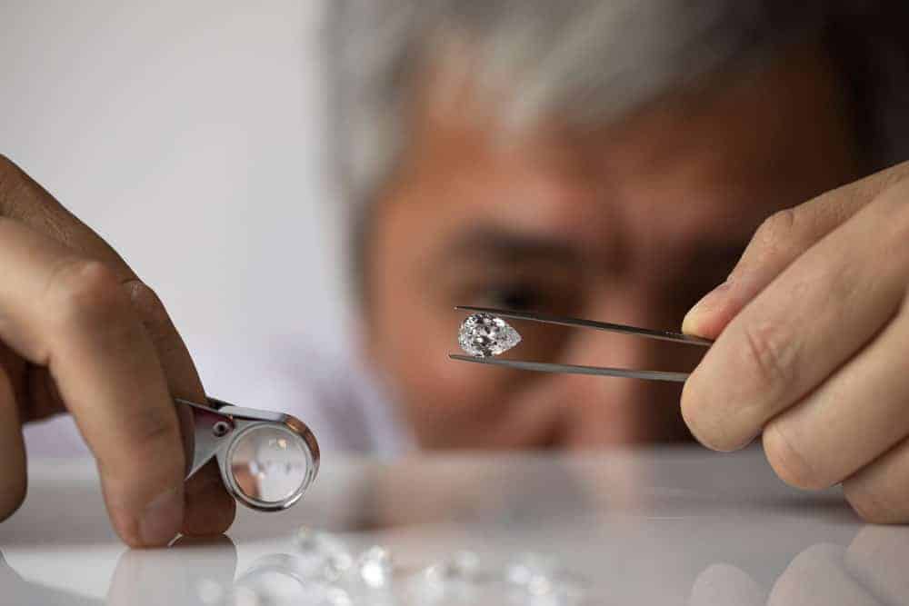 A jeweler looking at a pear-shaped diamond.