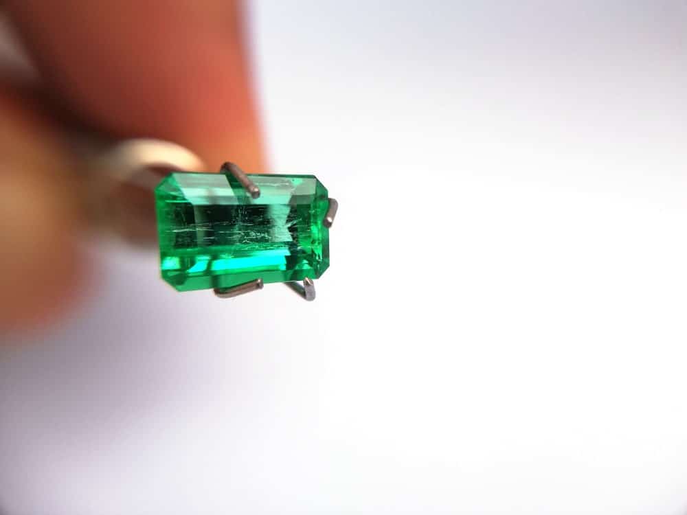 This is a close look at a Columbian emerald held with a pair of tweezers.
