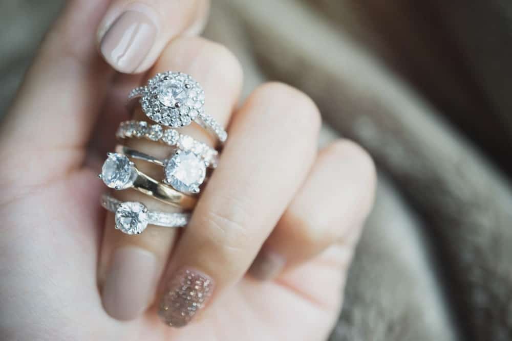 A woman wearing a variety of diamond rings on her finger.