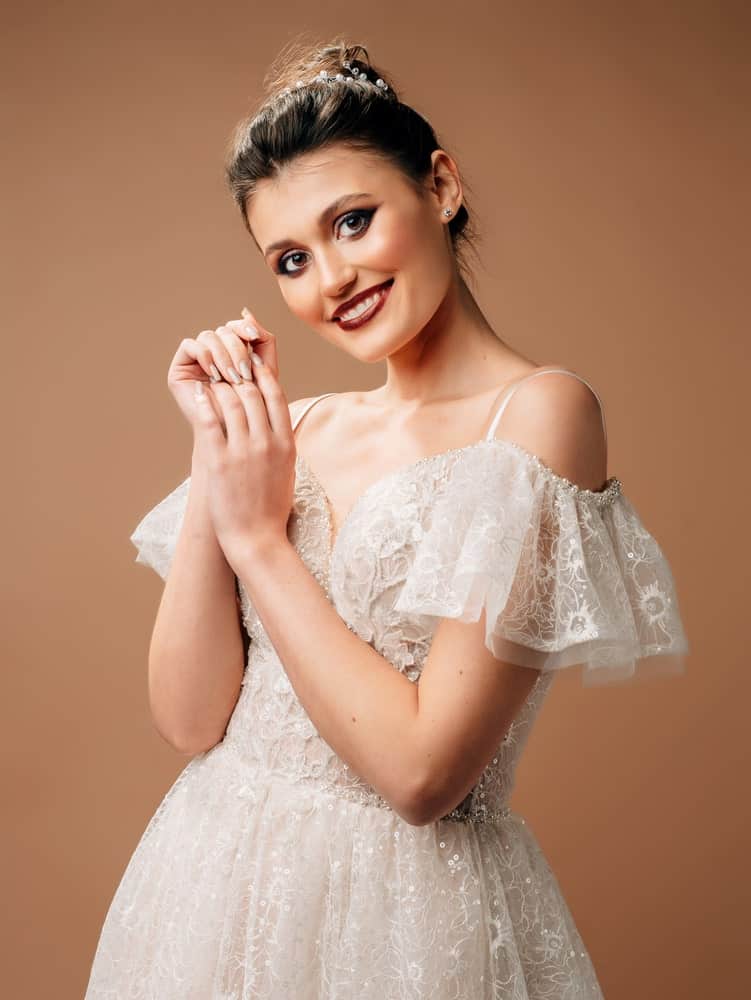 A woman wearing a white wedding dress that has flutter sleeves.