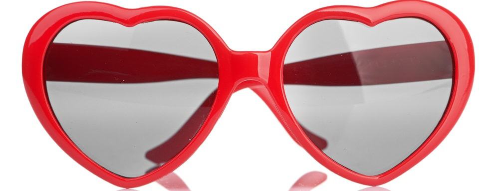 This is a close look at a pair of red heart-shaped sunglasses.