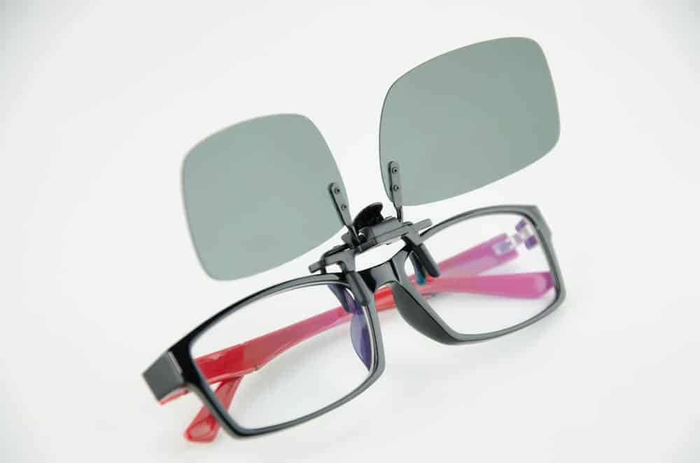 A pair of clip-on black sunglasses on a pair of reading glasses.