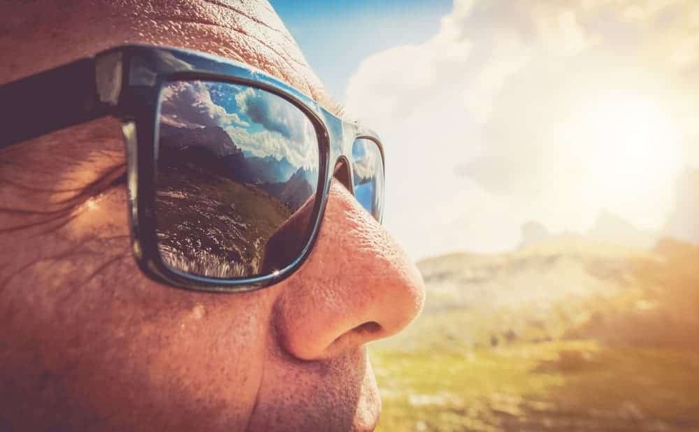 A close look at a man wearing a pair of sunglasses that protects his eyes from UV rays.