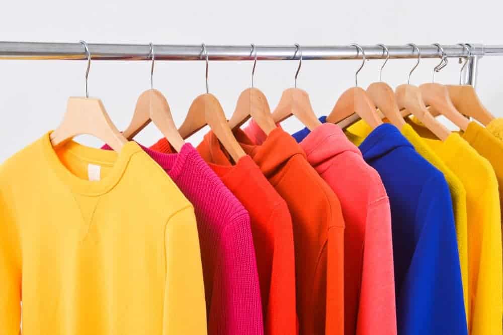 A close look at a rack of various colorful sweatshirts.