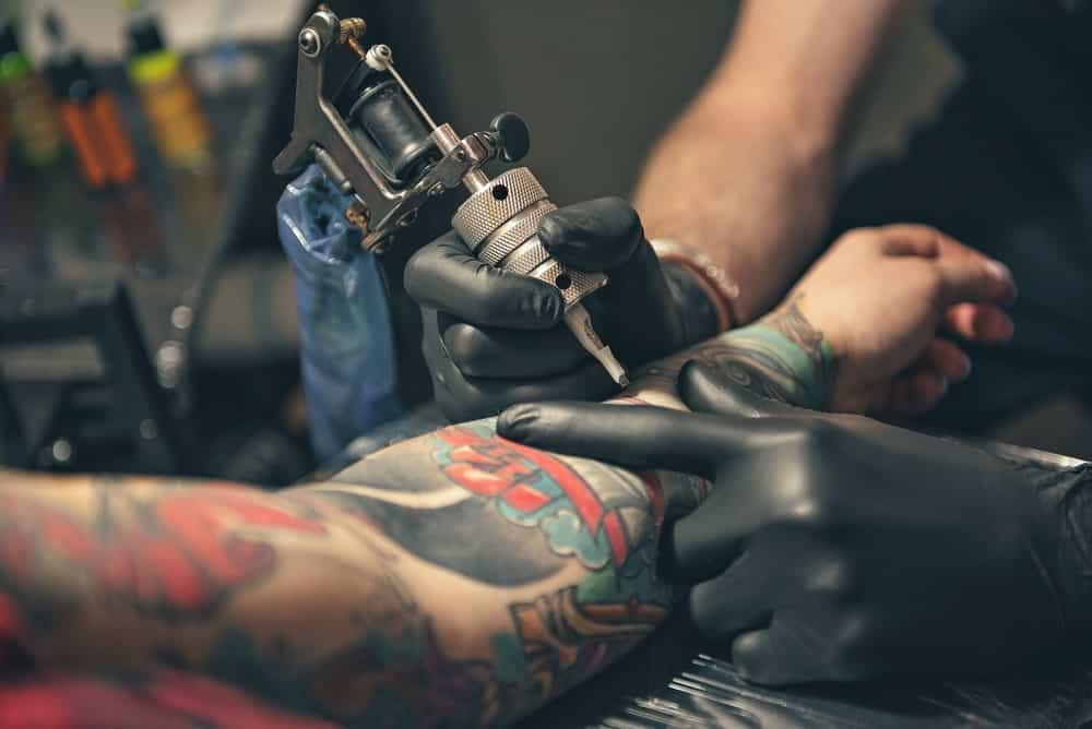 This is a close look at a man having his left arm tattooed.
