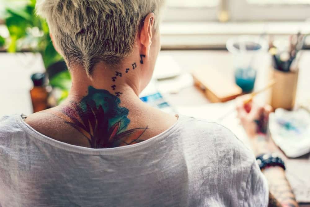 This is a close look at back of a woman with colorful tattoos.