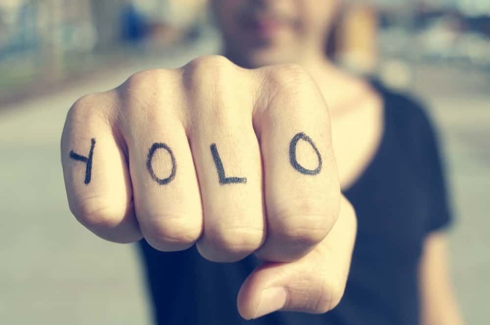 This is a close look at a man's fist with the letters YOLO tattooed on it.