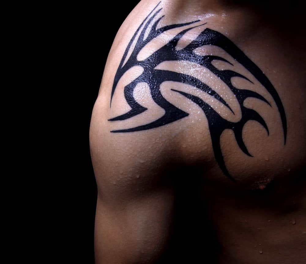 A close look at a man's shoulder with a tribal tattoo.