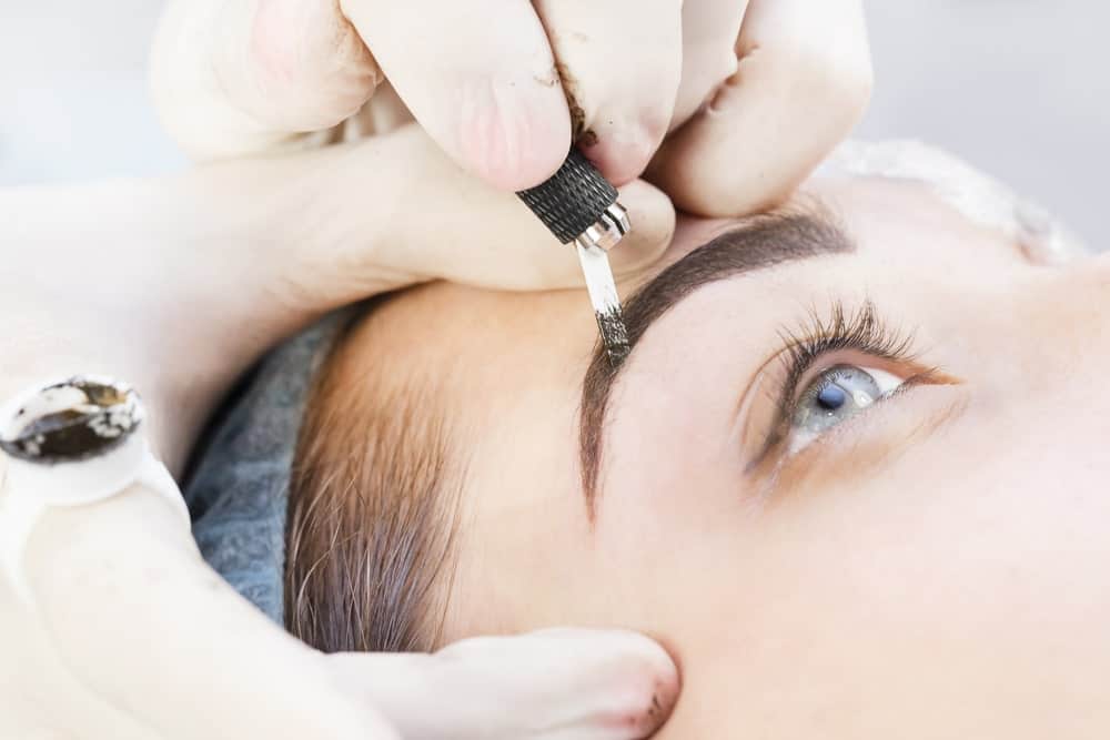 This is a close look at a woman having a cosmetic tattoo on her eyebrows.