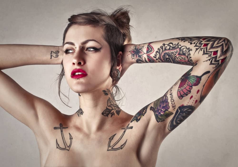 A woman with multiple tattoos on her arms and neck.