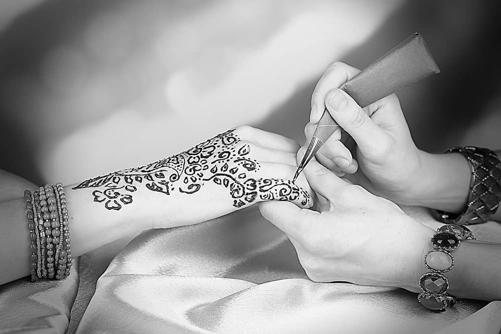 This is a close look at a woman's hand being tattooed with floral patterns.