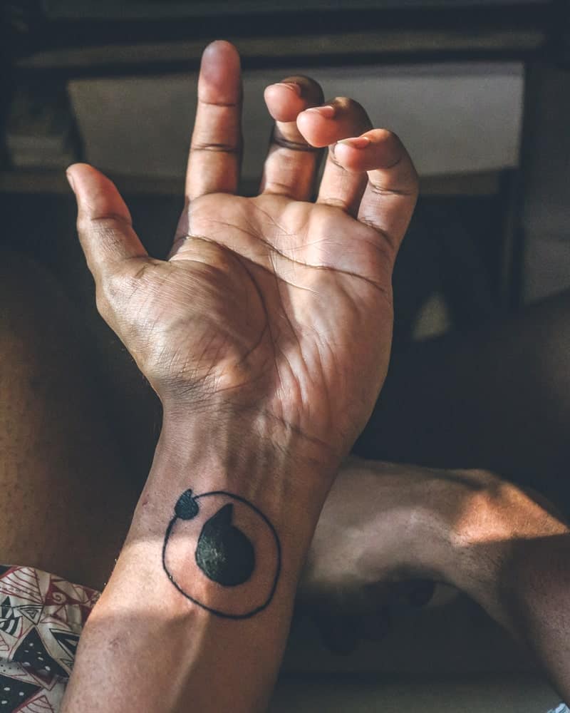 This is a close look at a man's wrist with a simple tattoo.