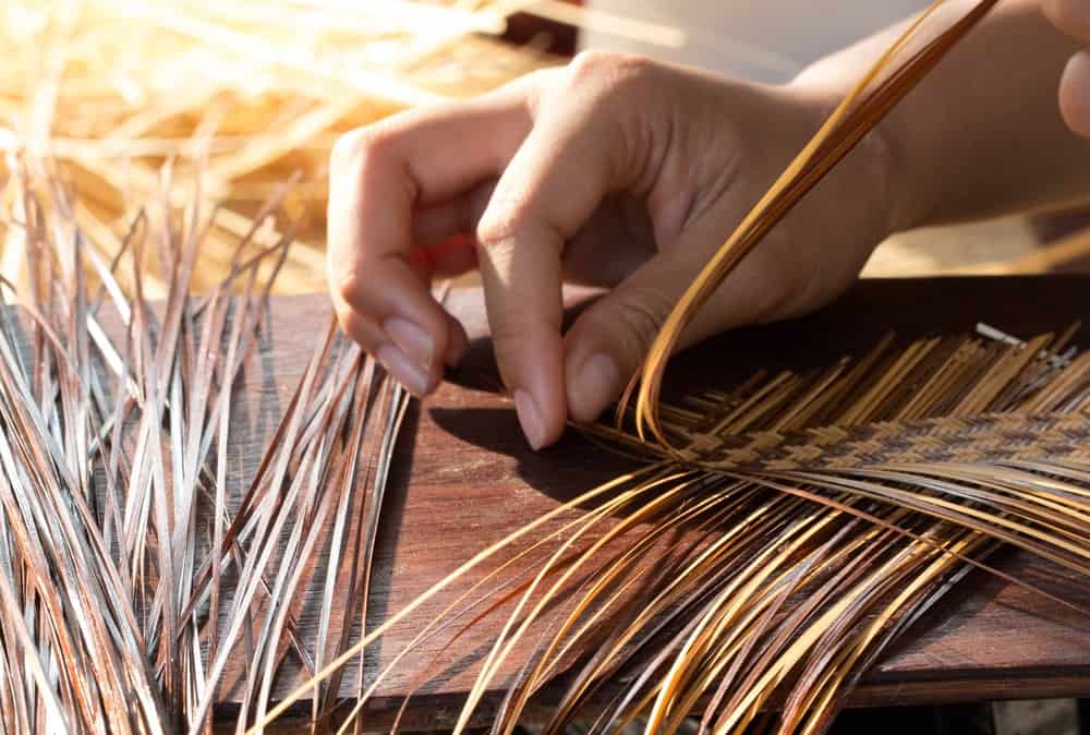 This is a close look at a pair of hands weaving a basket.