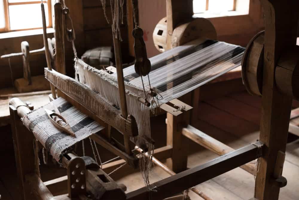 This is a close look at an old wooden loom within a wooden cabin.
