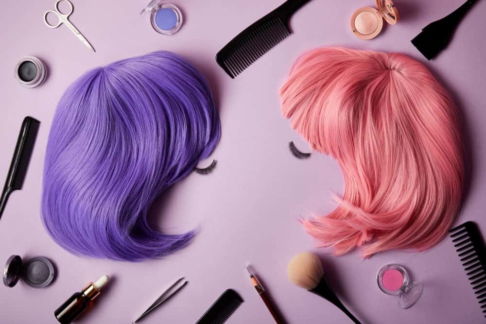 A pair of colorful wigs surrounded by accessories and beauty essentials.