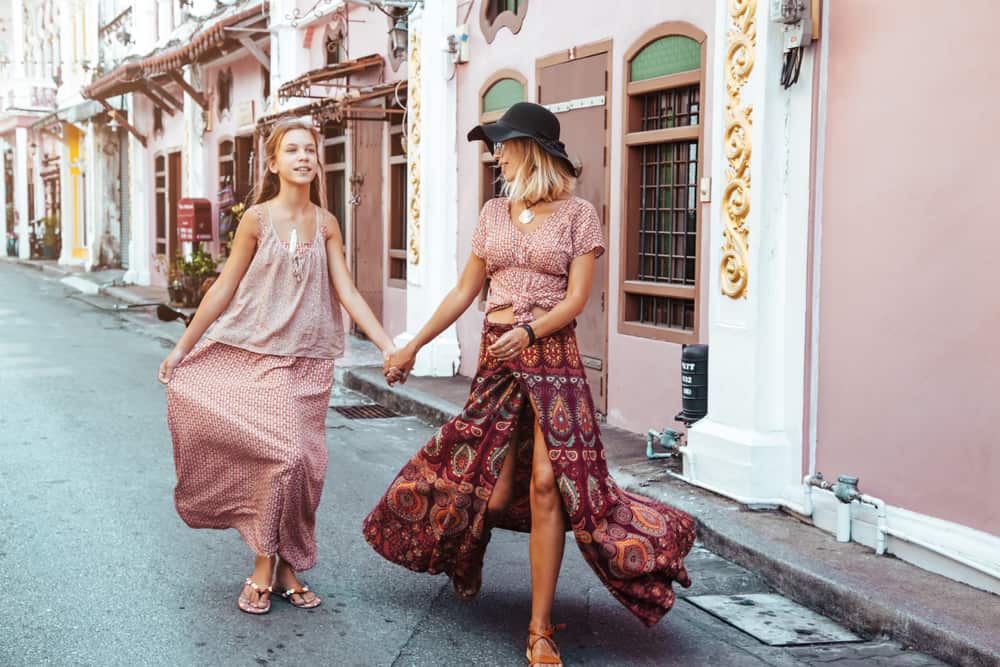Mom and daughter in bohemian dress walking down the street.
