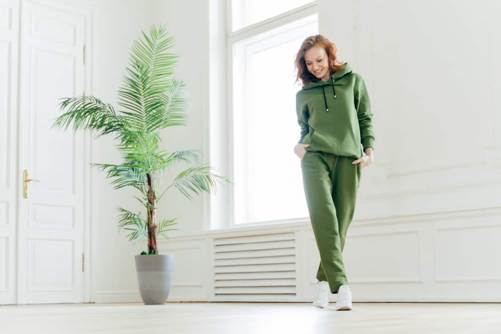 Woman in a matching green tracksuit exercising indoors.