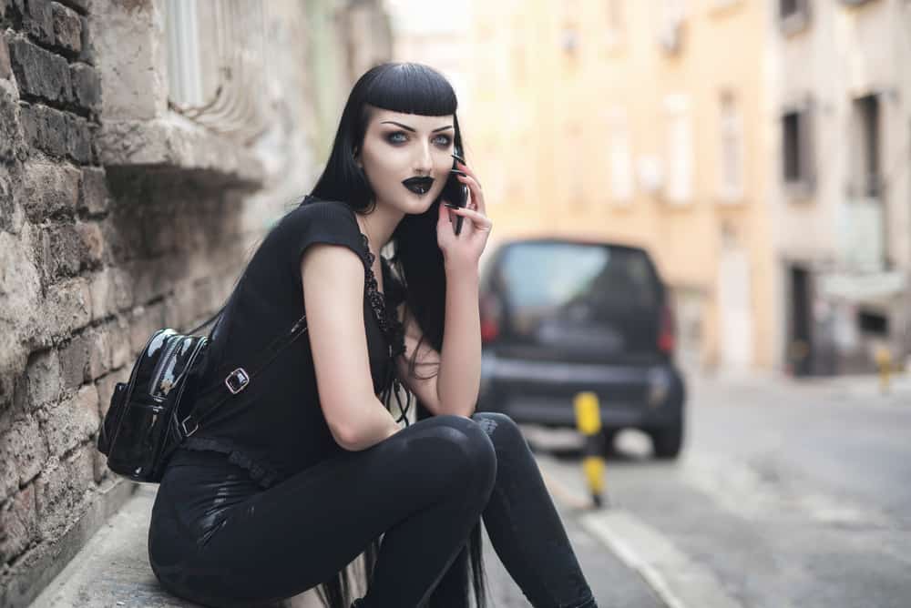 Goth girl sitting near the street.