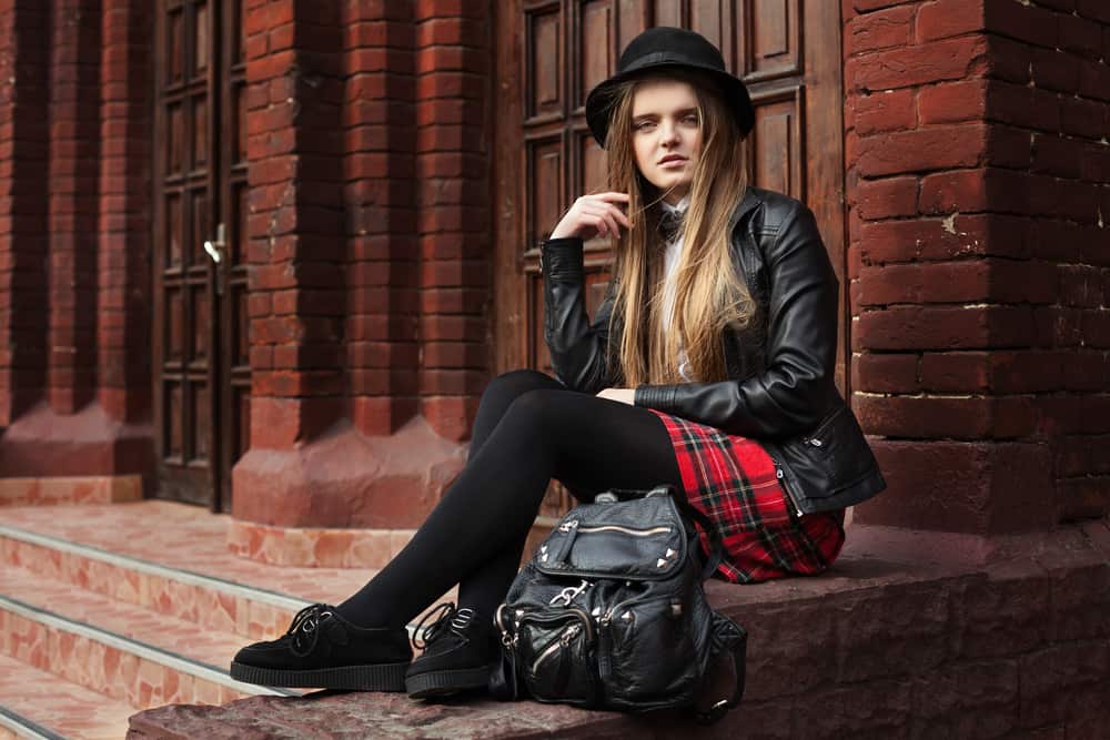 Woman in a ska outfit sitting on the stairs outside a building.