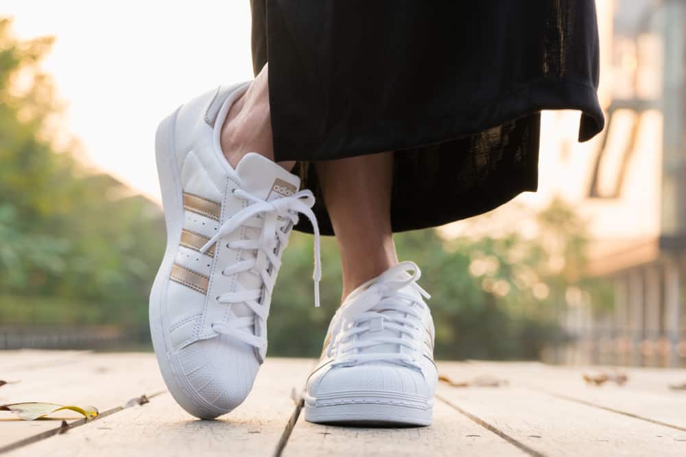 This is a close look at a woman wearing a pair of white Adidas sneakers.