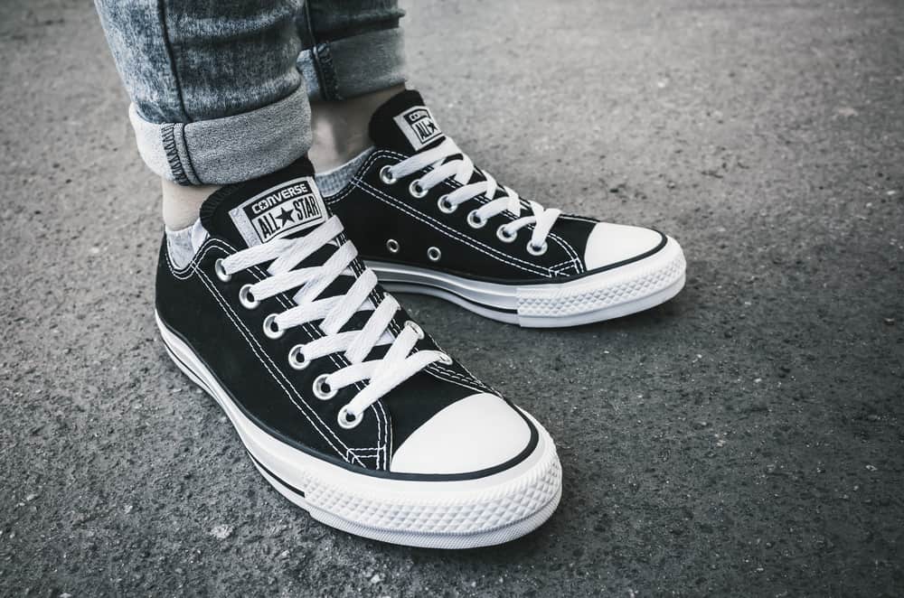 This is a close look at a woman wearing a pair of black Converse sneakers.