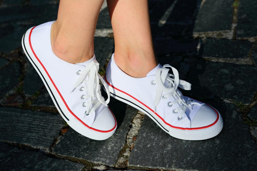 A close look at a woman wearing a pair of white Keds sneakers.