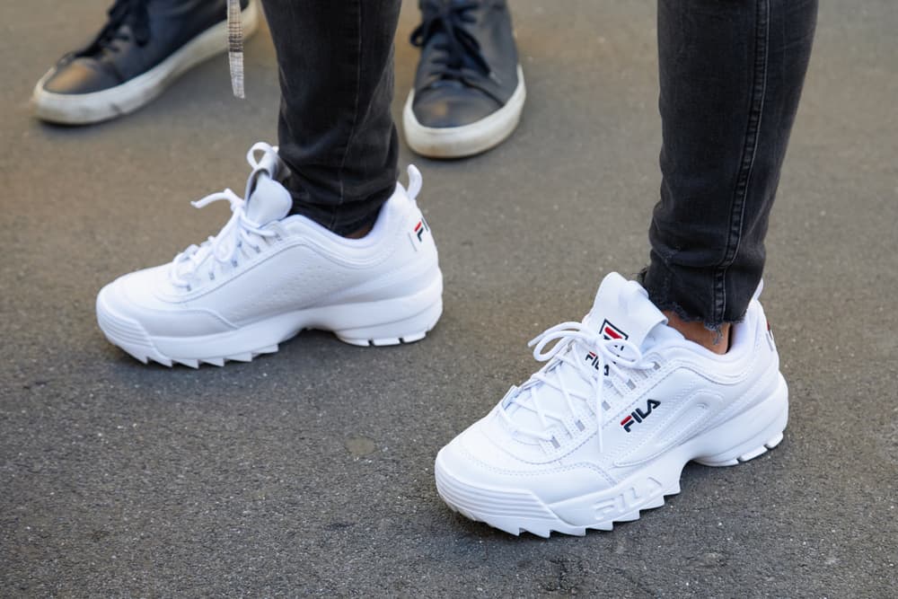 This is a close look at a man wearing a pair of chunky white Fila sneakers.