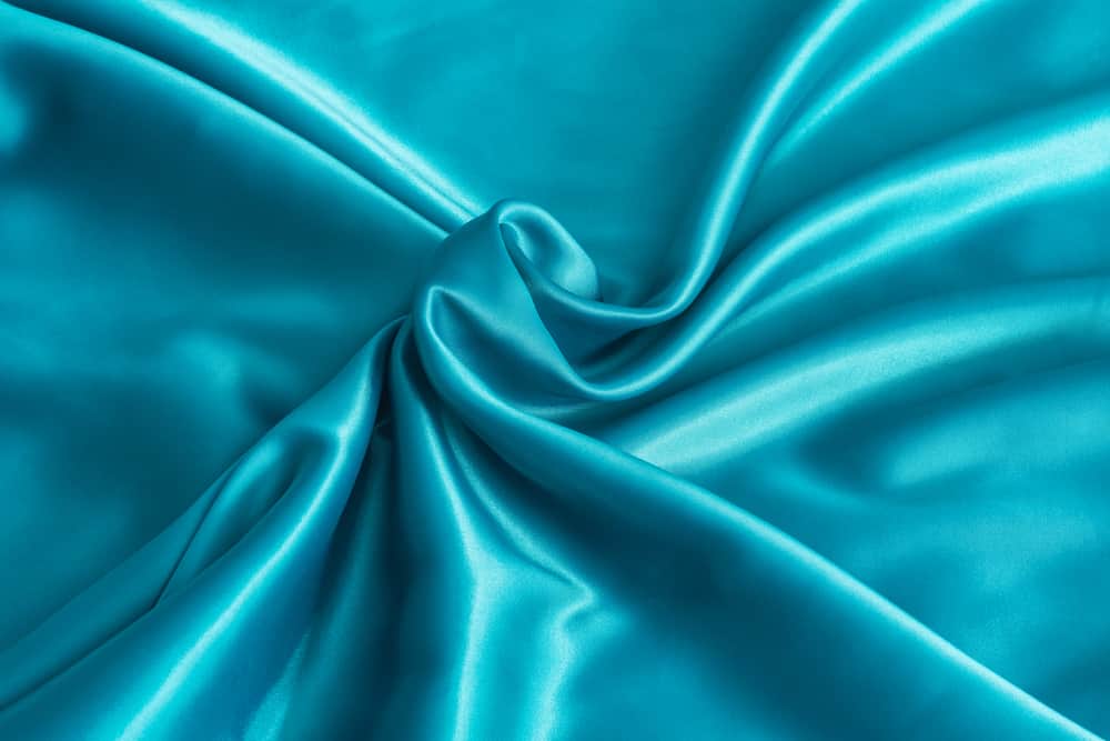 This is a close look at an aqua blue satin fabric.