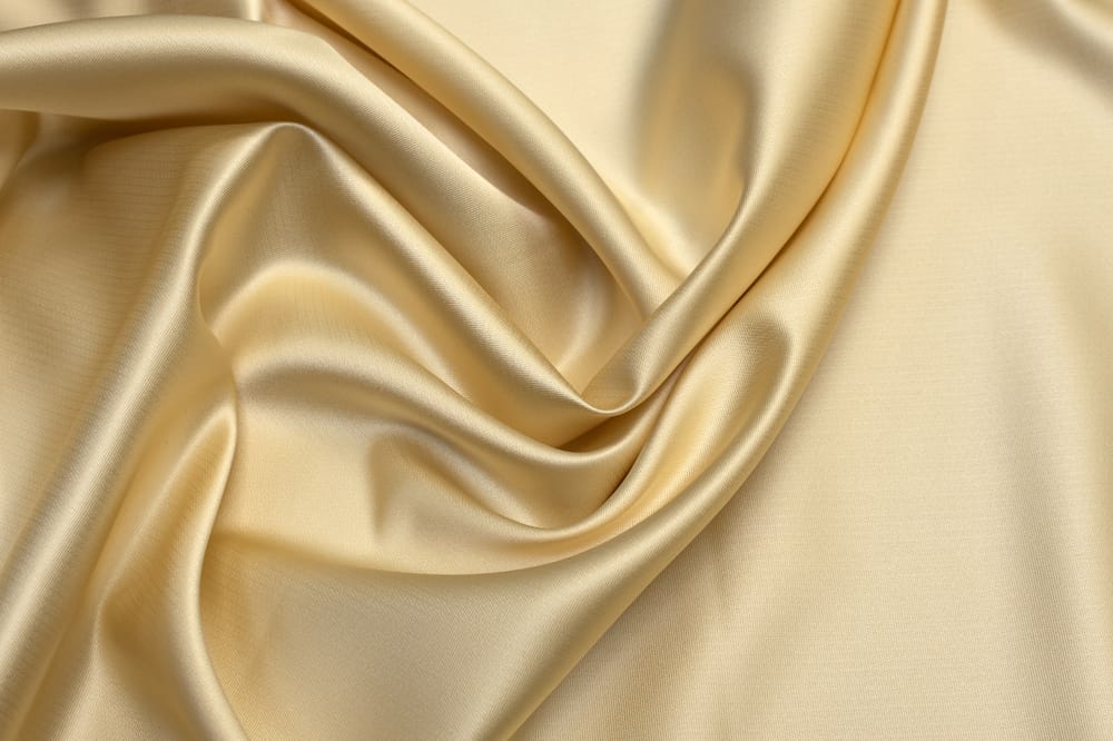 This is a close look at a silky Tafetta fabric with a golden hue.