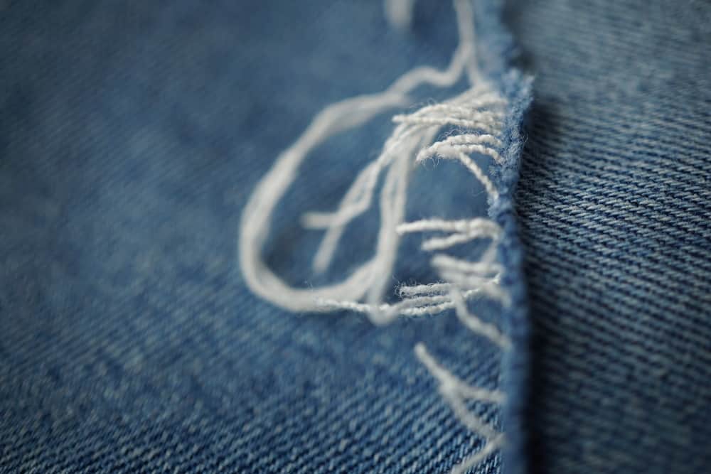 This is a close look at the frayed tear of a pair of blue jeans.