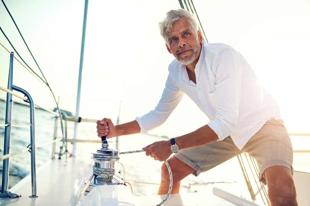 Man in a white polo standing on the deck of his boat.
