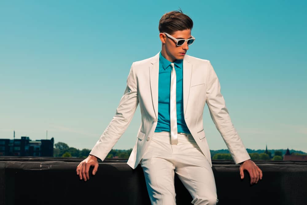 Man in vintage look wearing white suit and glasses.
