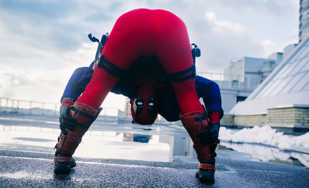 This is a close look at a Deadpool cosplayer posing on a building rooftop.