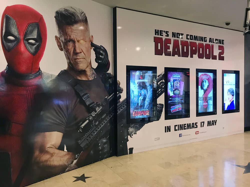 This is a close look at a coming soon wall display at a theater featuring a Deadpool 2 poster.