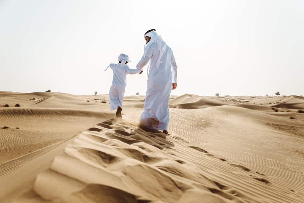 An Arabic man with his son on the desert.