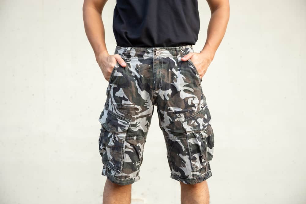 A man wearing a pair of camouflage print tactical shorts.