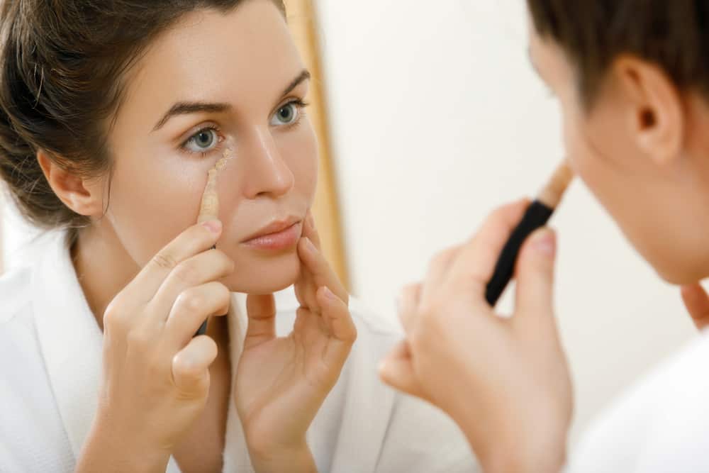 Woman using concealer for under eye circles.