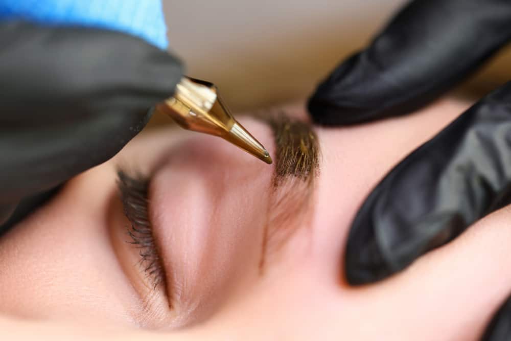 Cosmetologist performing eyebrow microblading.