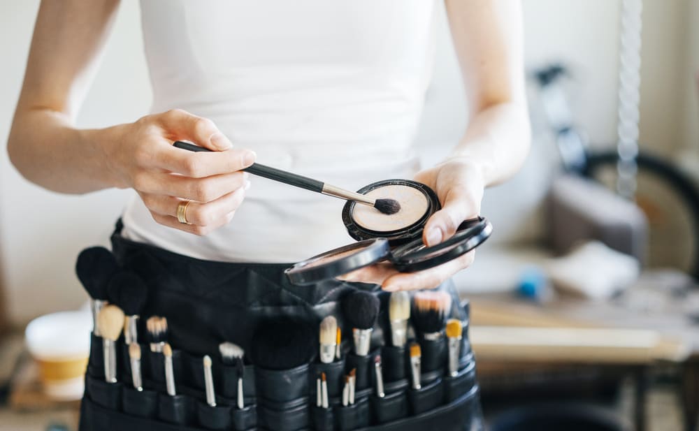 Professional make-up artist with a belt bag with various brushes.