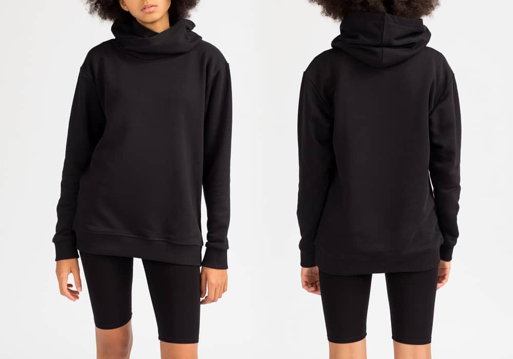 This is a front and back view of a woman wearing a black hoodie with her black shorts.